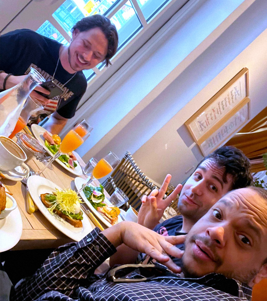 Three handsome men sitting at a table with food